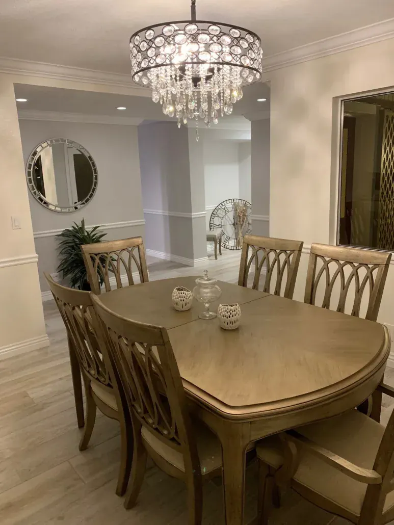 Dining room with a crystal chandelier, crown molding and wood-look tile after an interior remodel
